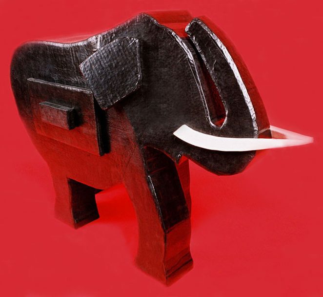 Éléphant en carton sculpté, noir avec des défenses blanches sur fond rouge.