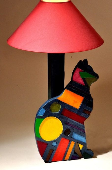 Lampe en forme de chat, avec un abat-jour rouge et un design coloré et géométrique.